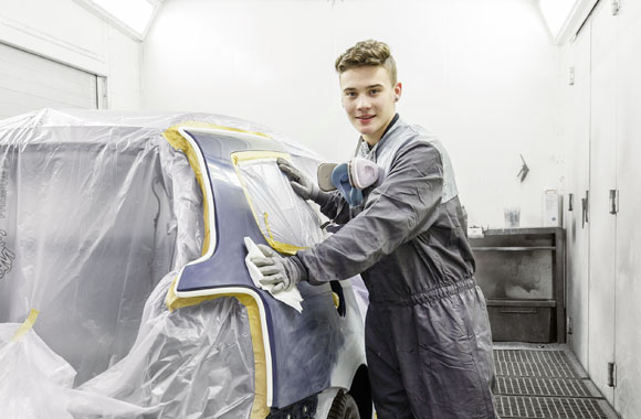 Fahrzeuglackierer lackiert ein Auto