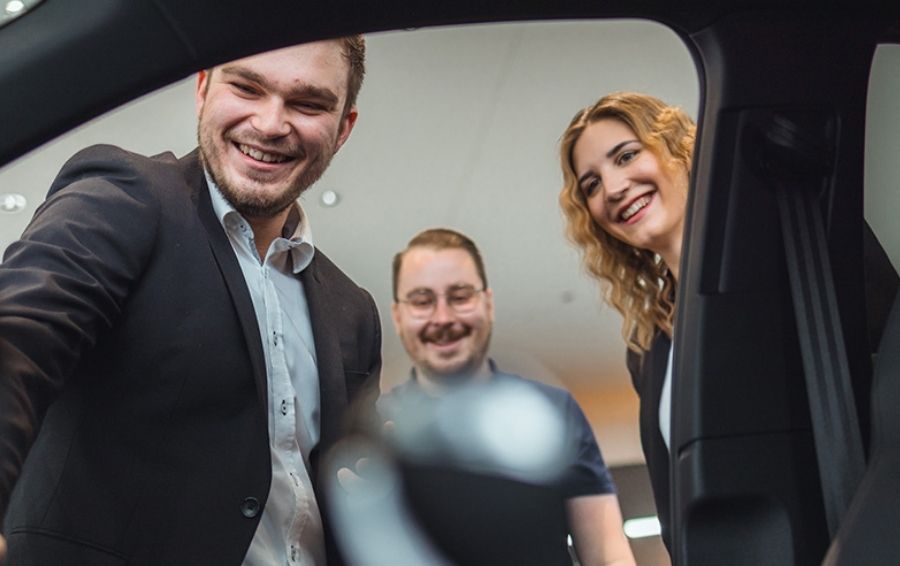 Drei Verkäufer die in den Innenraum eines Auto blicken